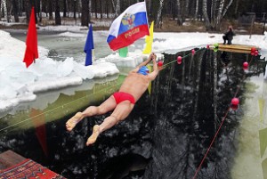 A member of a local swimming club holds a Russian national flag as he dives in at the start of a 24-hour swimming marathon near the western Siberian city of Barnaul March 29, 2014. Thirty members of the club will swim in turn during the event, held to mark Crimea becoming part of Russia, local media reported.  REUTERS/Andrei Kasprishin (RUSSIA - Tags: POLITICS SPORT SWIMMING TPX IMAGES OF THE DAY) - RTR3J2KY